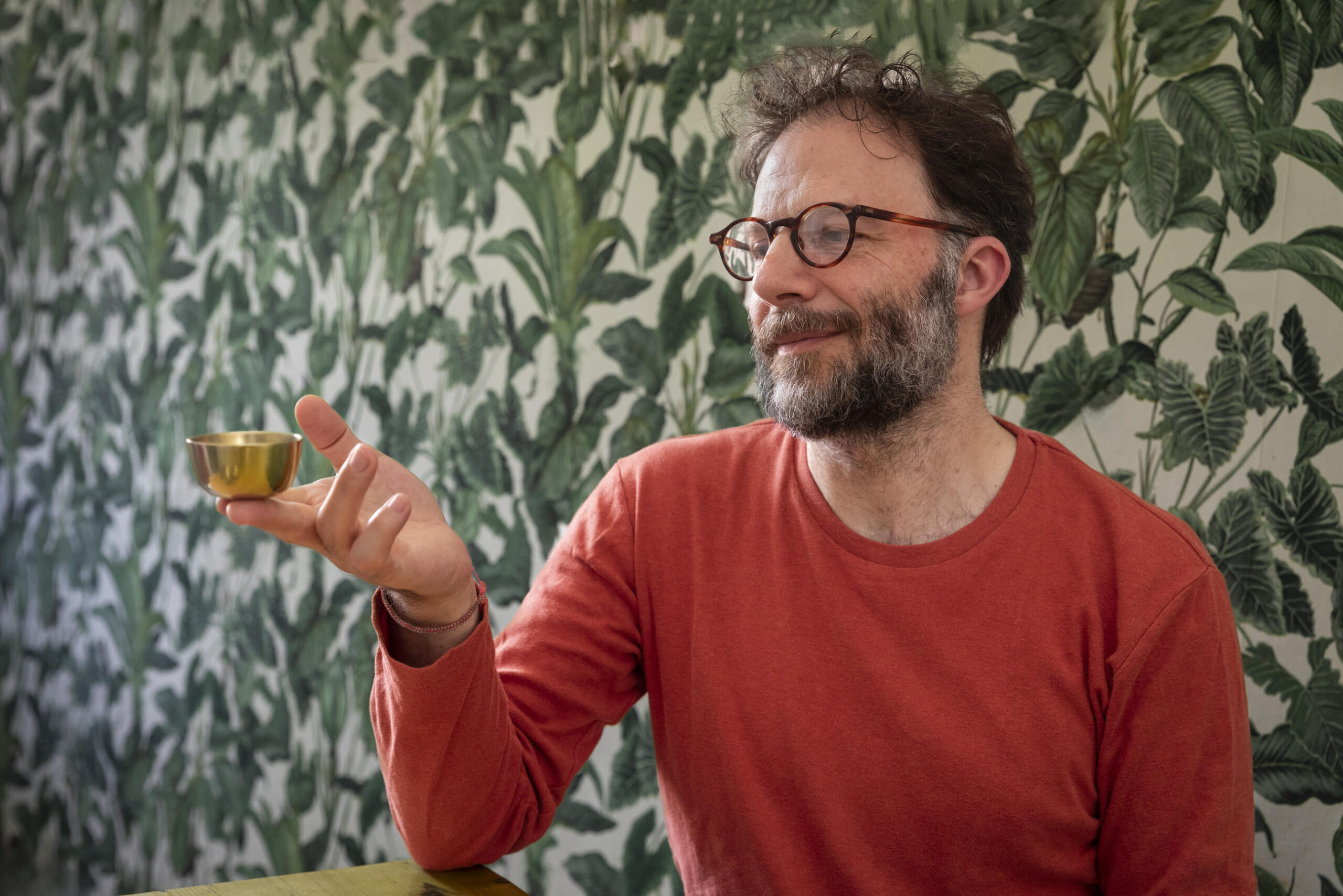 Nicolas Monguzzi tenant un bol chantant Zen en métal doré, vêtu d’un t‑shirt rouge orangé, photographié par Sheldon Suter à Locarno le 12 juillet 2024